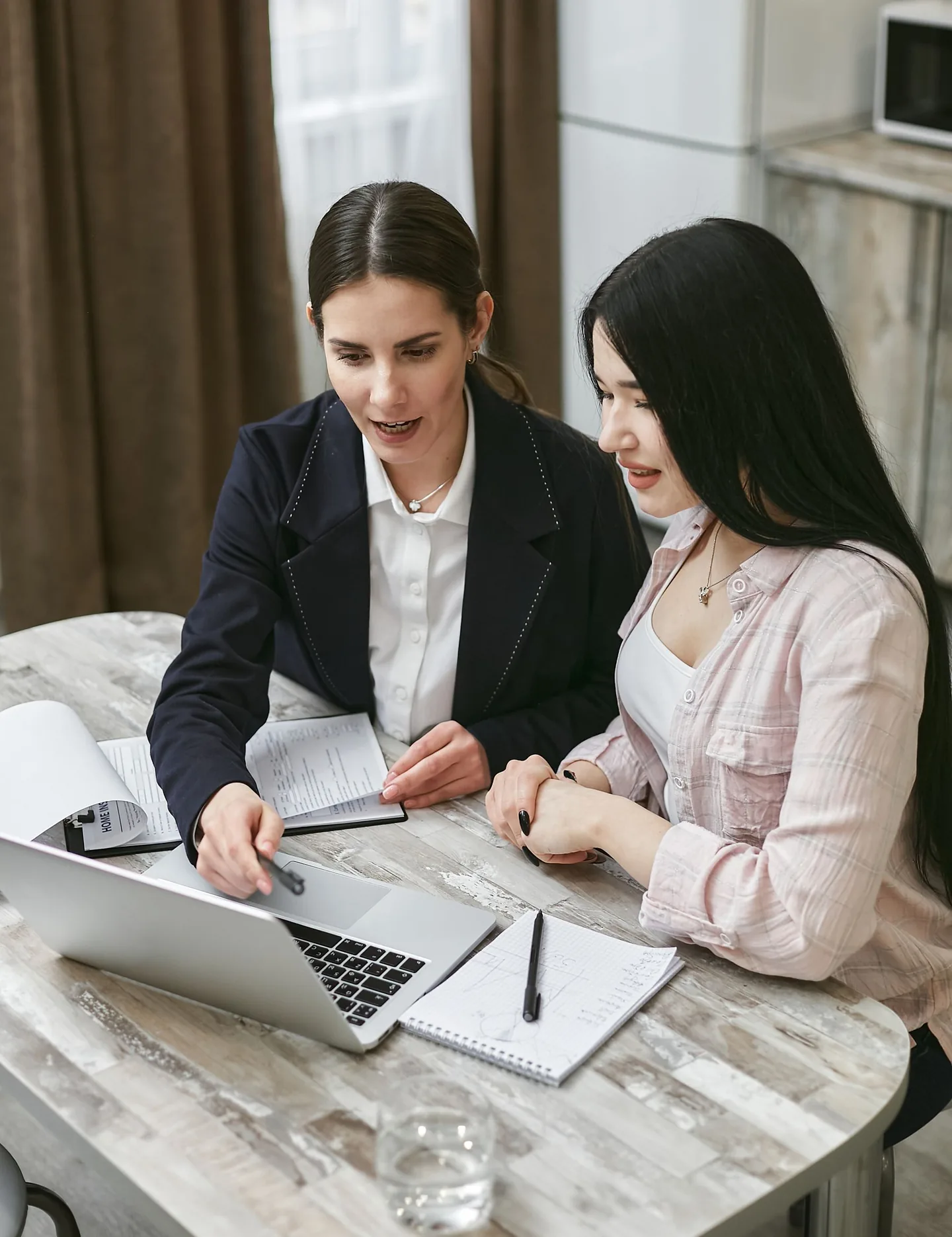 Two professionals discussing information on a laptop.
